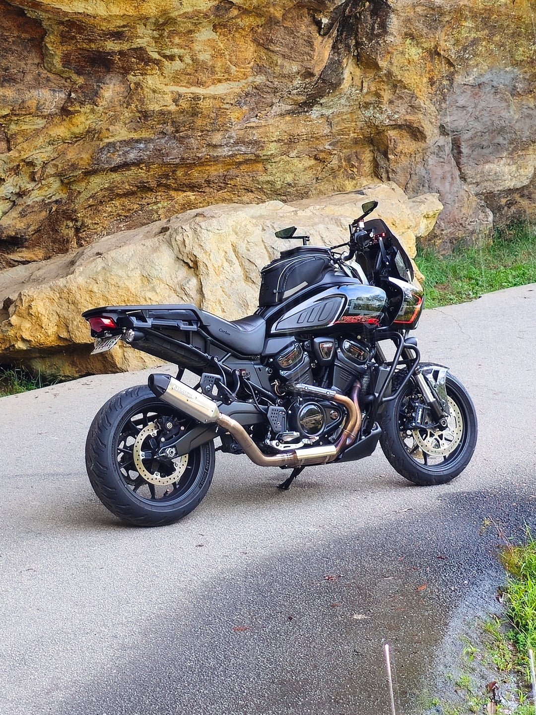 Harley-Davidson Pan America parked by a rock wall with a Stealth Pipes slip-on exhaust