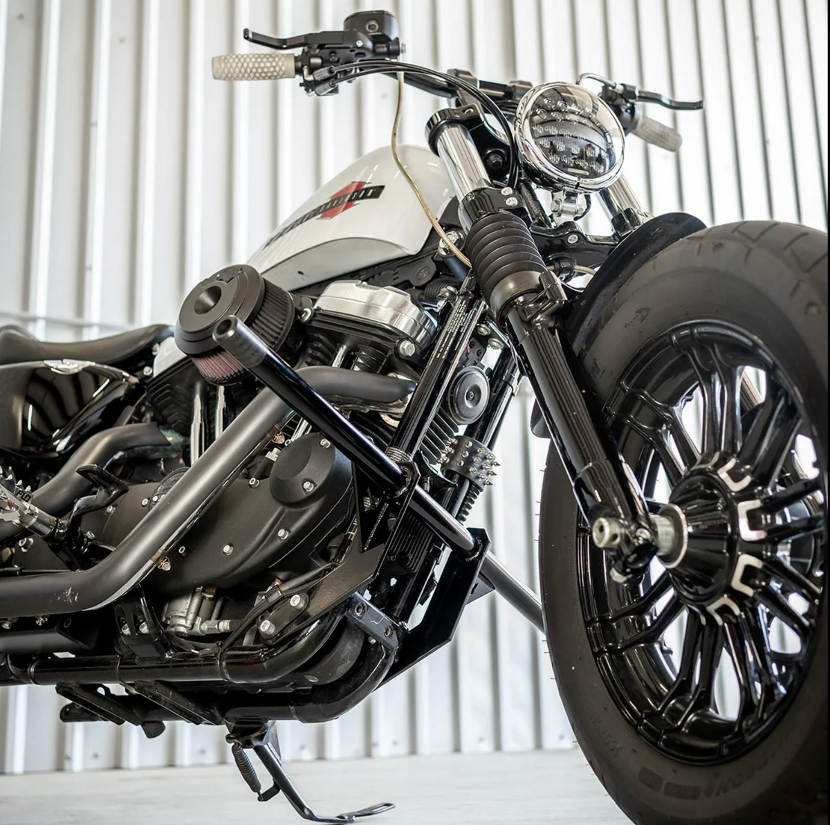 A black front crash bar installed on a Harley Davidson Sportster motorcycle, featuring two Delrin sliders., photo 3 of 6